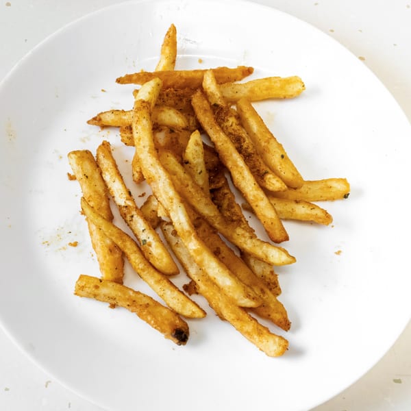 Golden-brown seasoned french fries piled on a white plate, ready to be enjoyed at Fried Shack.